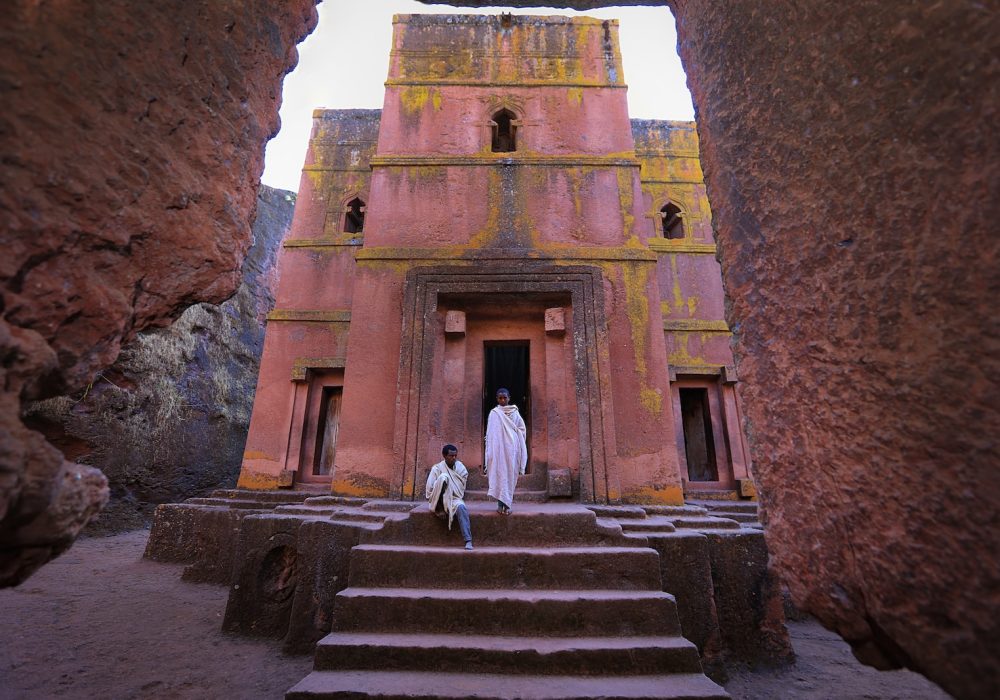 person in white dress in front of pink building